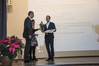 Foto: Ein Absolvent präsentiert seine Urkunde.