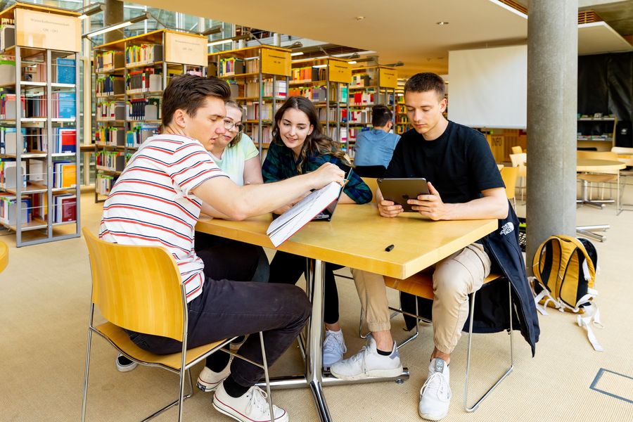Gruppe junger Menschen am Tisch sitzend in einer Bibliothek