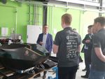 Foto: Ein Mann steht hinter einem Elektro-Rennauto und spricht mit Mitgliedern des WHZ-Racing Teams, die von hinten zu sehen sind.