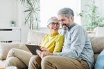 Mann und Frau sitzen auf der Couch und schauen auf ein Tablet.