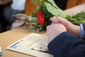 Foto: Gefaltete Hände liegen auf einer Urkunde Rasmussen-Preis 2018.
