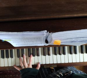 Abgebildet ist ein Klavier von oben, auf dem eine Hand spielt.