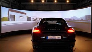 Foto: Ein Fahrzeug steht im Fahrsimulator vor einer virtuellen Streckenführung auf der Leinwand.