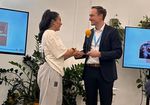 ein Frau mit schwarzen Haaren und ein Mann bei der Übergabe eines Preises
