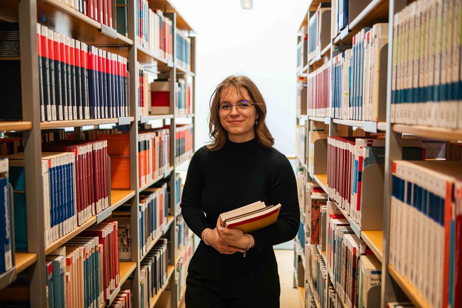 Eine Studentin steht in der Hochschulbibliothek. 