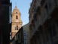 Foto: Blick auf einen Kirchenturm durch eine Häusergasse.