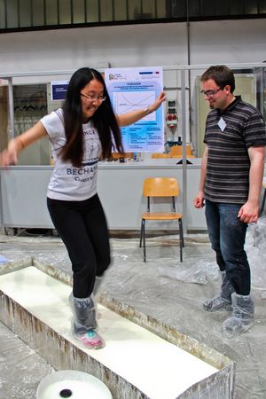 Foto 2: Eine Besucherin balanciert in einer länglichen Kiste mit einem Gemisch von Maisstärke und Wasser gefüllt ohne einzusinken zur Langen Nacht der Technik 2015. Fotoquelle: WHZ/AMB