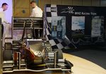 dunkelgrauer Elektro-Rennwagen auf einem Holzboden zur Präsentation