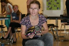 Foto: Ein Mädchen in der Hocke hält ihr Modellauto in der Hand.