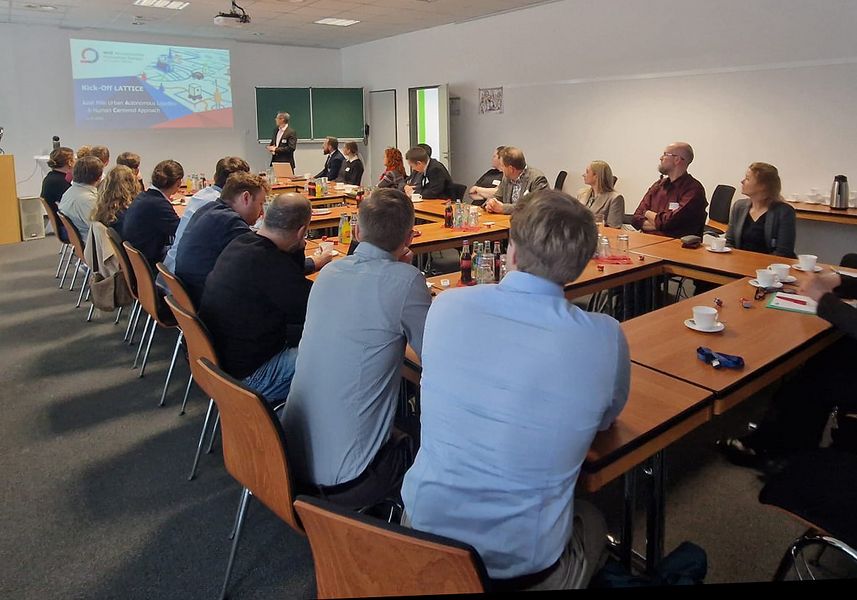 Personen sitzen in einem Seminarraum und verfolgen eine Präsentation. 