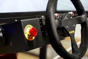 Foto: Lenkrad des Fahrsimulators mit daneben liegendem Notaus Knopf.