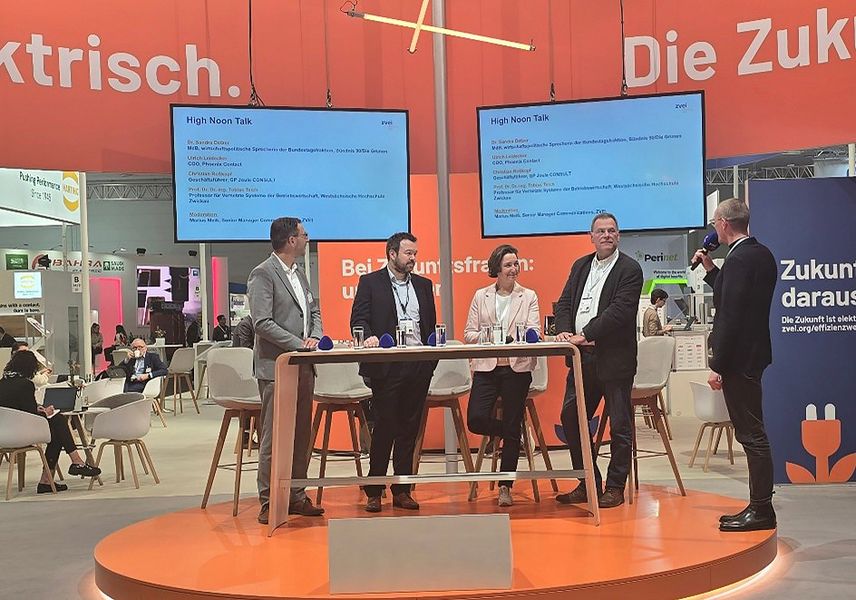 Eine Diskussionsrunde, 4 Personen stehen auf Podium in einer Messehalle, Moderator stellt Fragen. 