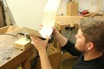 Foto: Ein Student prüft den Holzrohling eines Musikinstrumentes.