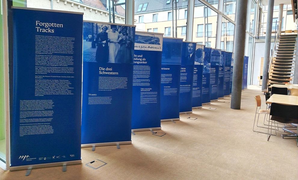 Blaue Roll-Ups mit Bildern und Texten stehen in einem modernen Raum. 