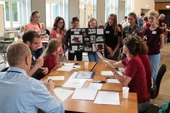 Foto: Eine Gruppe Schülerinnen präsentiert am Jury Tisch ihr Präsentationsplakat und ihr Solar Modellauto.