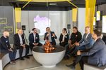 Eine Gruppe Menschen sitzt im Halbkreis um ein künstlihes Lagerfeuer und diskutiert.