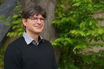 Foto: Ein Mann steht vor einem Baum und schaut freundlich in die Kamera. Es ist ein Portraitfoto.