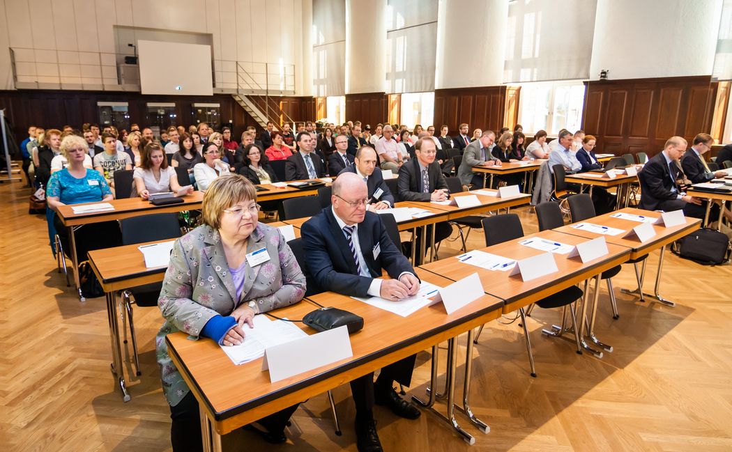 Foto: Teilnehmer sitzen in der Aula und hören einem Vortrag zu.