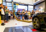 Ein Fahrzeug wird auf einem Prüfstand getestet. Viele Personen stehen drum herum.