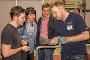 Foto 3: Ein Mitarbeiter zeigt Besuchern die Handinnenfläche seines angezogenen Handschuhes. Rückblick zur Langen Nacht der Technik 2015. Foto 3: WHZ/AMB