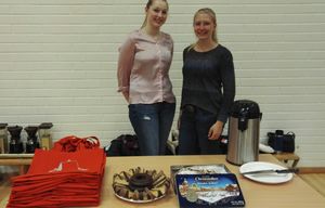 Foto: Zwei Studierende stehen hinter einem Tisch mit Kuchenteller und einem Stapel Beutel darauf.