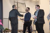 Foto: Vier Absolventen erhalten eine Gratulation und bekommen ihre Urkunden überreicht.