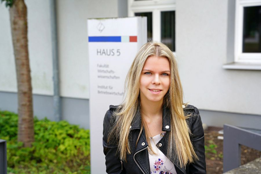 Foto: Eine junge Frau steht vor einem Schild der WHZ.