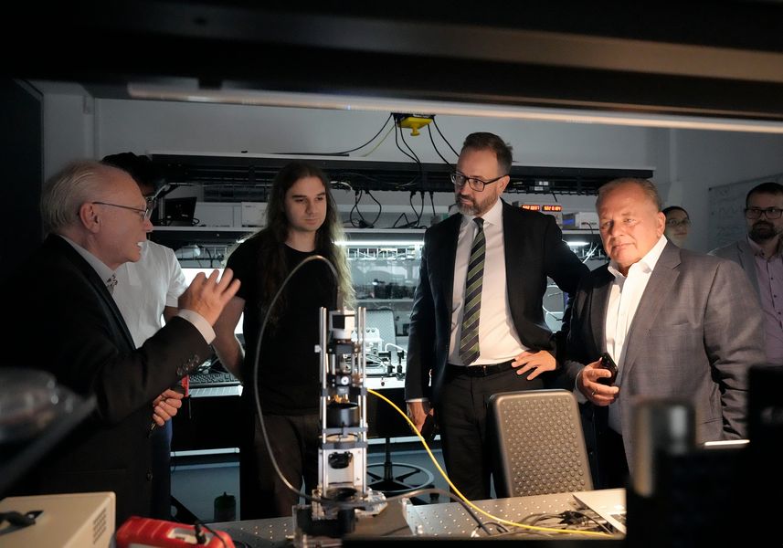 Personen betrachten einen Versuchsaufbau in einem Optik-Labor. 