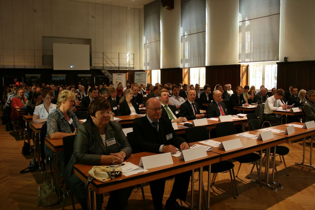 Foto: Teilnehmer sitzen in der Aula und hören einem Vortrag zu.
