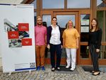 Foto: Gruppenbild mit 4 Personen. Vor einem Eingang der medizinischen Servicestelle stehend.
