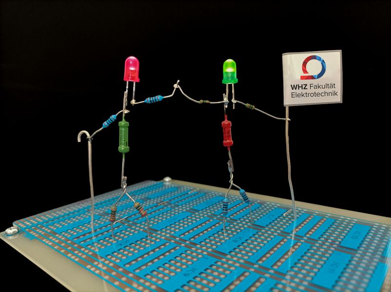 Foto: 2 selbst gelötete LED Männchen halten eine Flagge mit der Aufschrift Fakultät Elektrotechnik