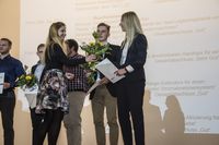 Foto: Fünf Absolventen bekommen eine Gratulation und Blumen überreicht.
