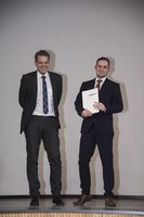 Foto: Ein Absolvent mit Zeugnis und Professor.