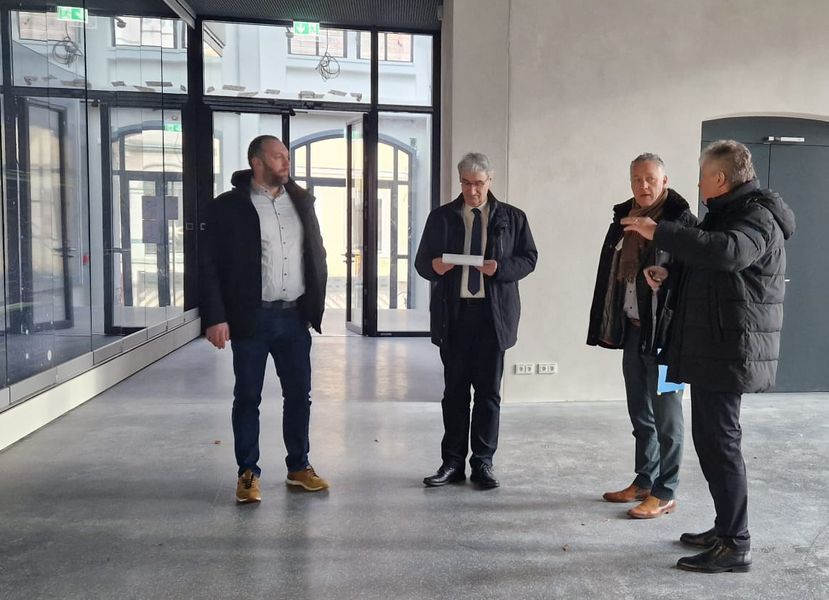 Vier Personen stehen in einem Foyer une sprechen über den Baufortschritt. 