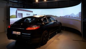 Foto: Ein Fahrzeug steht im Fahrsimulator vor einer virtuellen Streckenführung auf der Leinwand.