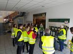 Foto: Eine Gruppe Studierender stehtt bei einem Werksbesuch und erhält gerade einen Vortrag.