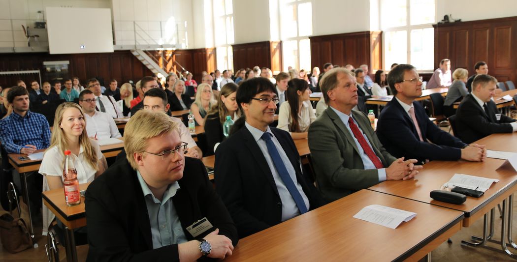 Foto: Teilnehmer sitzen in der Aula und hören einem Vortrag zu.