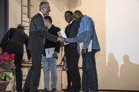 Foto: Drei Absolventen erhalten eine Gratulation und bekommen Urkunden überreicht.