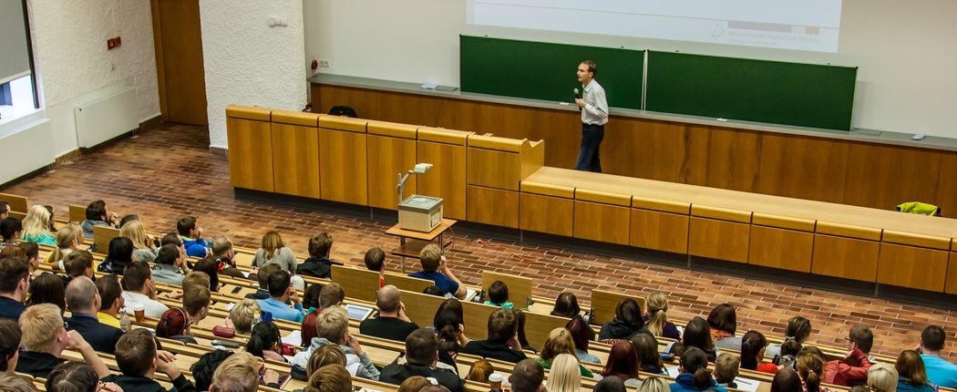 Foto: Studierende sitzen im Hörsaal und hören einer Vorlesung zu.