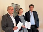 Foto: Eine Frau und zwei Männer haben einen Vertrag in der Hand.
