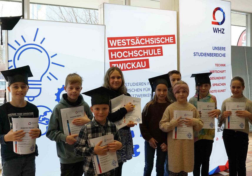 Kinder stehen vor Leuchtdisplays und halten Zeugnisse in der Hand. 