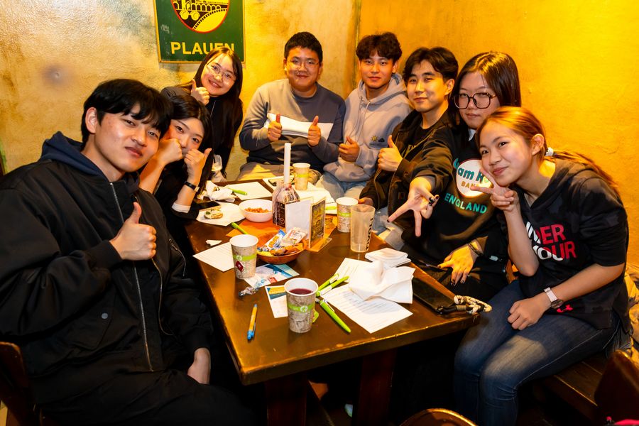 Acht Personen sitzen um einen Tisch und schauen fröhlich.