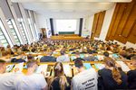 Ein vollbesetzter Hörsaal, von hinten fotografiert.