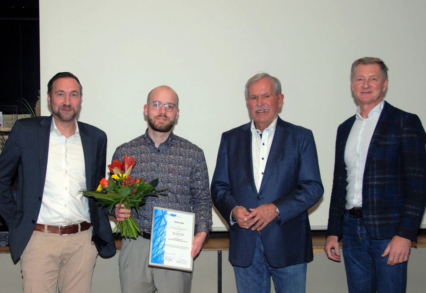 Vier Gründungsmitglieder der DVS-Studierendengruppe blicken in die Kamera. Der Vorsitzende hält einen Blumenstrauß und Urkunde in der Hand.