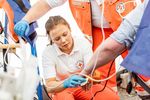 Nofallsanitäterin legt Zugang am Arm eines Patienten
