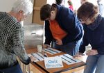 Personen stehen um einen Tisch mit Zetteln und beantworten Fragen
