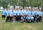 Gruppe von jungen Frauen und Männern in hellblauen Sportshirts auf einer grünen Wiese