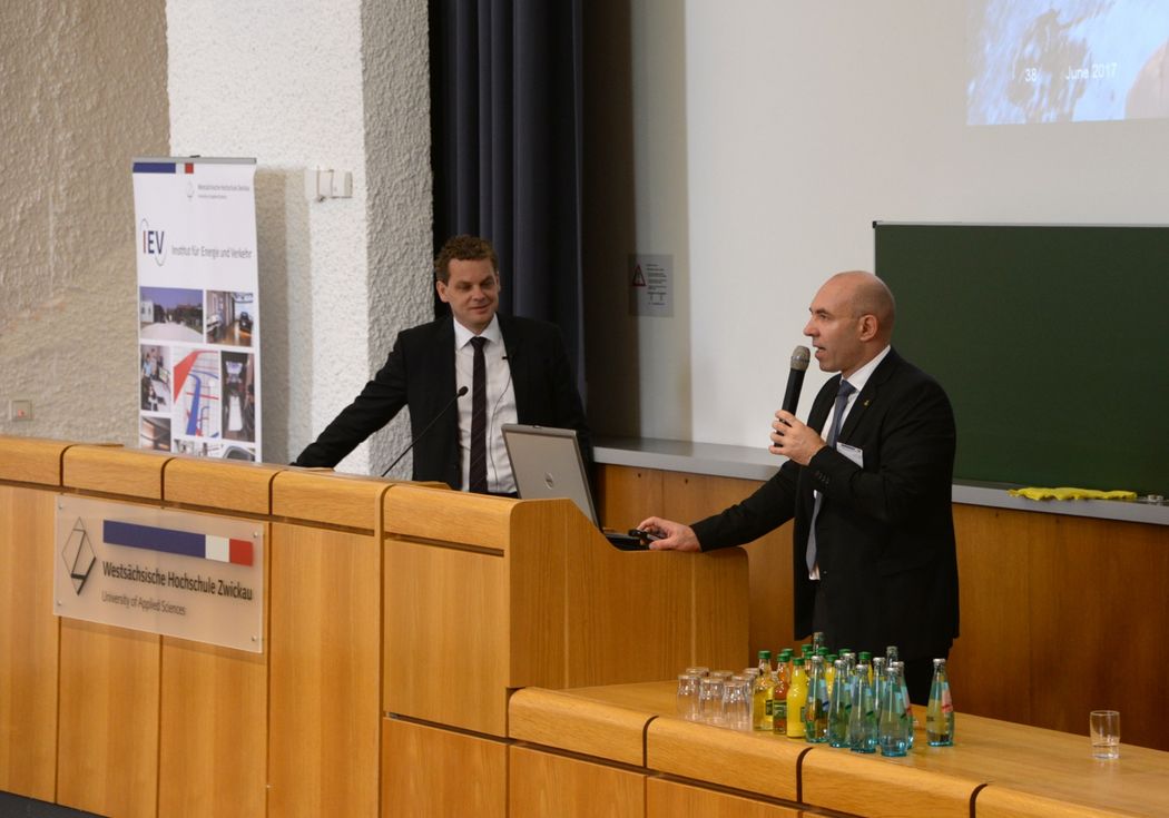 Foto: 2 Professoren zum Kolloqium im Hörsaal am Pult stehend.