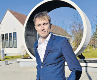 Person (Prof. Dr. rer. medic. Tom Schaal) vor Loopingskulptur
