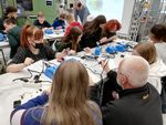Schülerinnen löten Bauteile in einer Werkstatt. Mitarbeiter der Hochschule geben Hilfestellungen.
